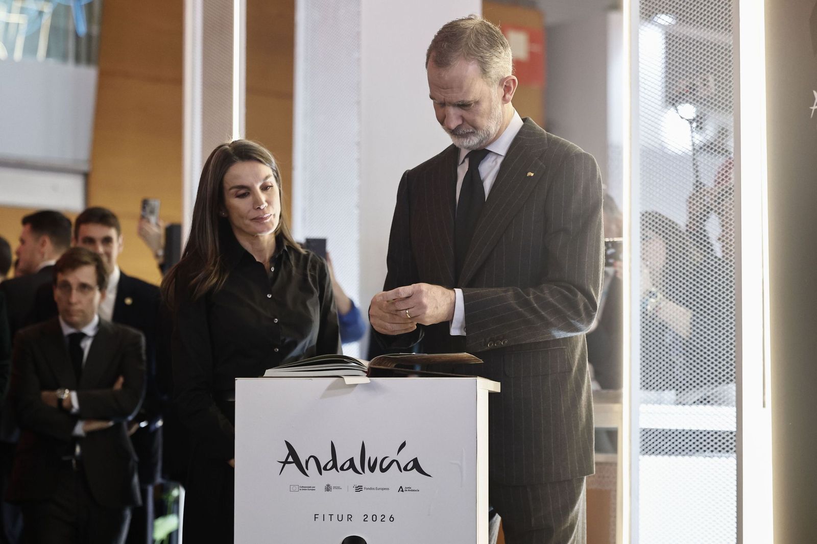Los reyes de España firman en el libro de condolencias en el pabellón de Andalucía en Fitur.