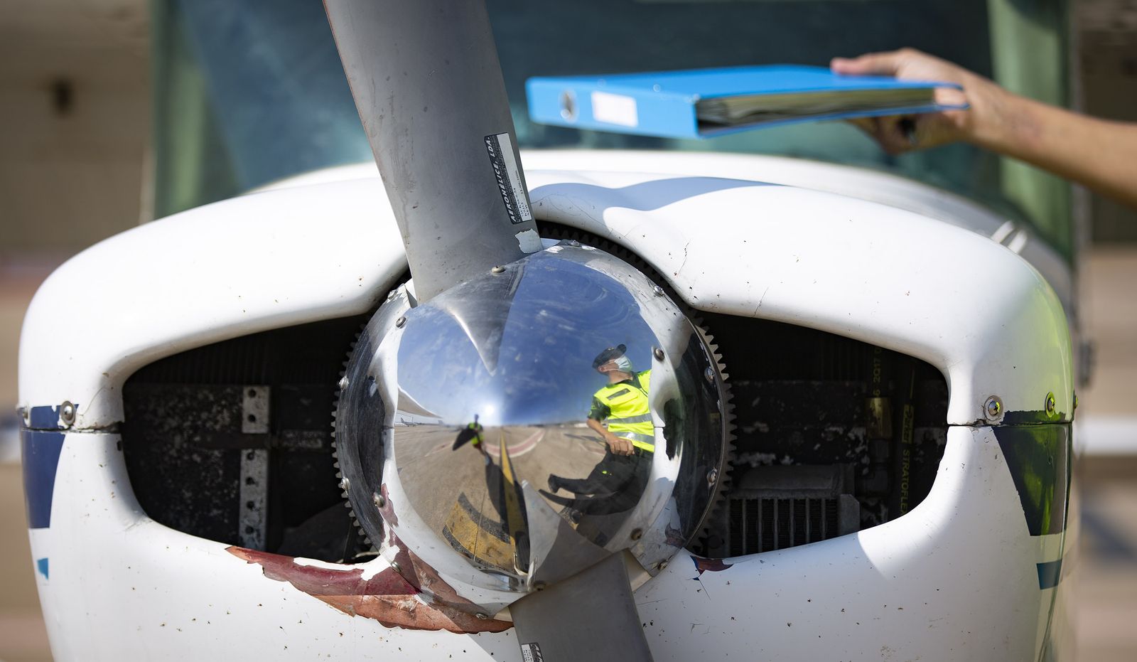 Un guardia reflejado en la hélice de una avioneta.