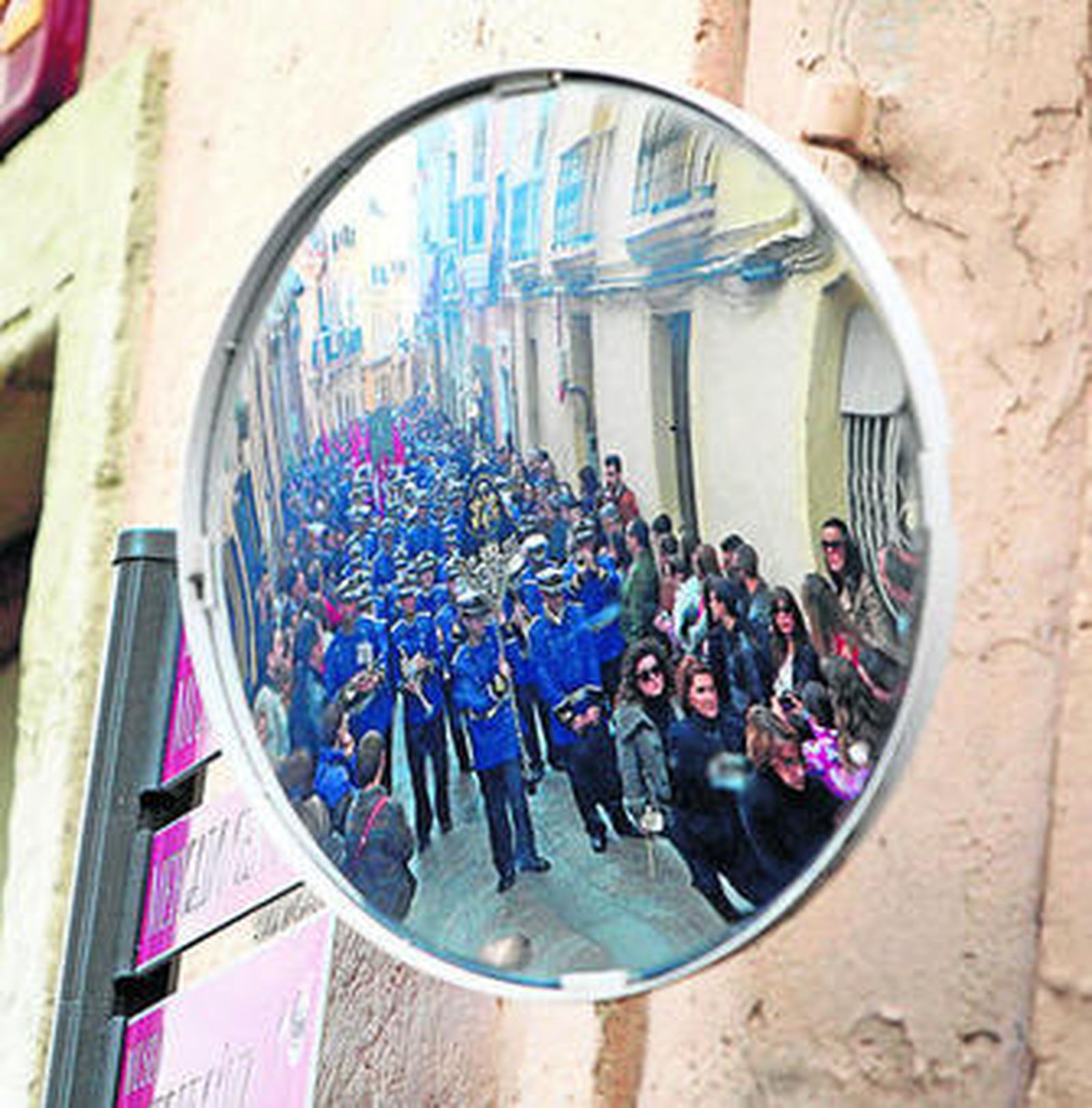 Público, penitencia y banda reflejados en un espejo de esquina, a la salida de Las Penas.