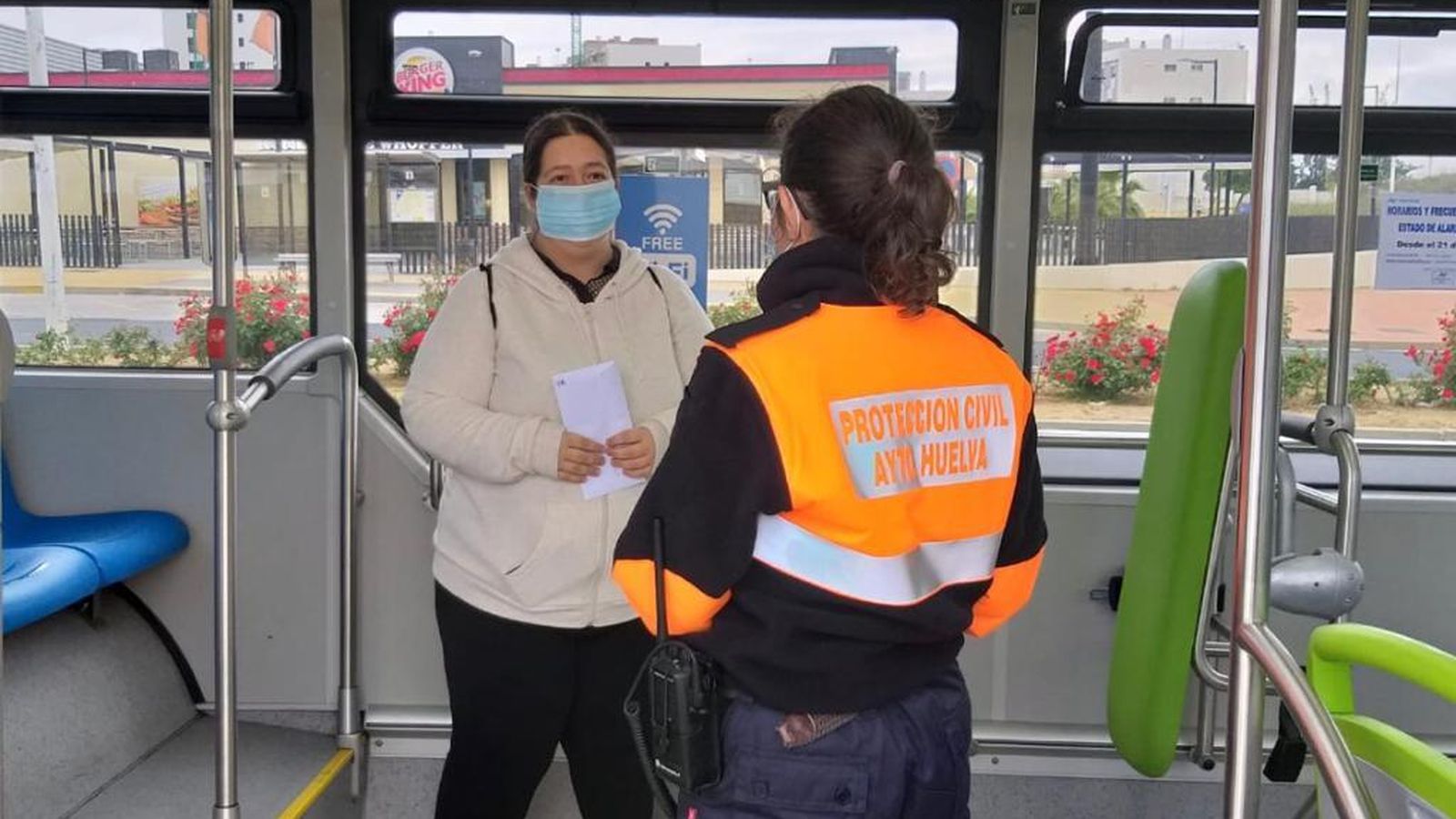 Una voluntaria de Protección Civil informa sobre el uso de mascarillas en el autobús.