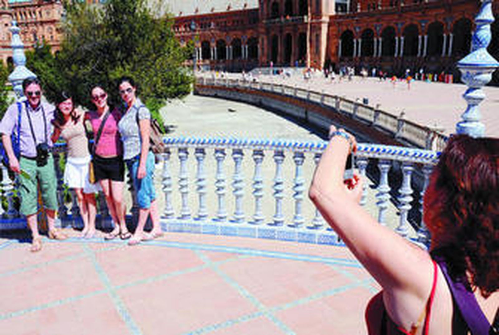 Un grupo de visitantes se fotografía en el estanque vacío de la Plaza de España que Emasesa recuperará ahora.