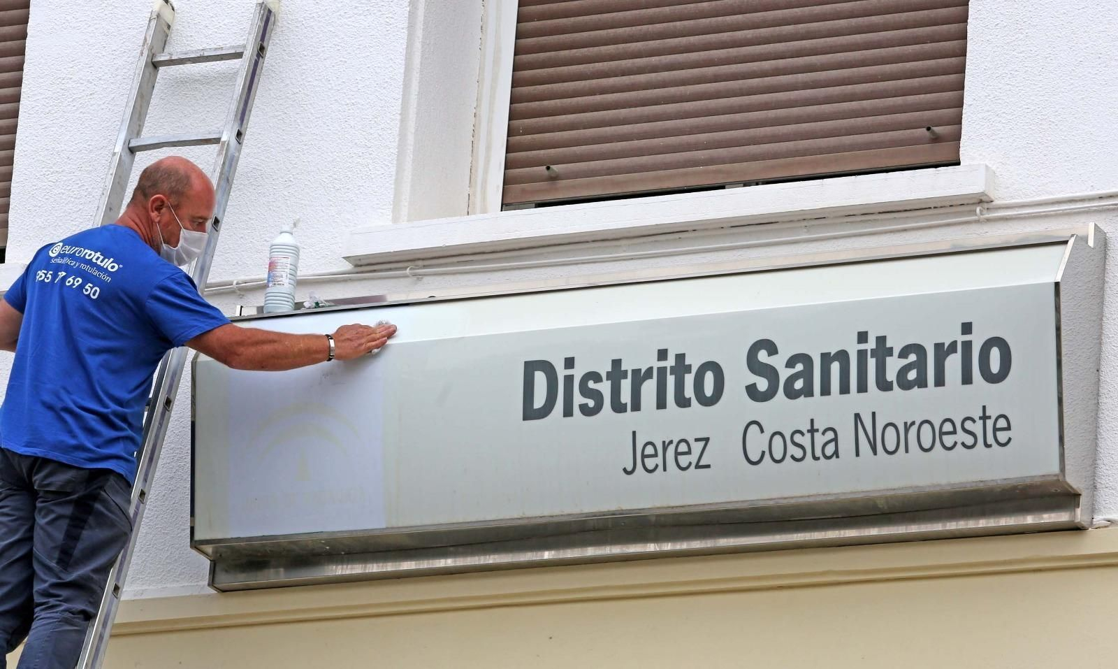 Un trabajador limpia uno de los carteles del hospital de Jerez.
