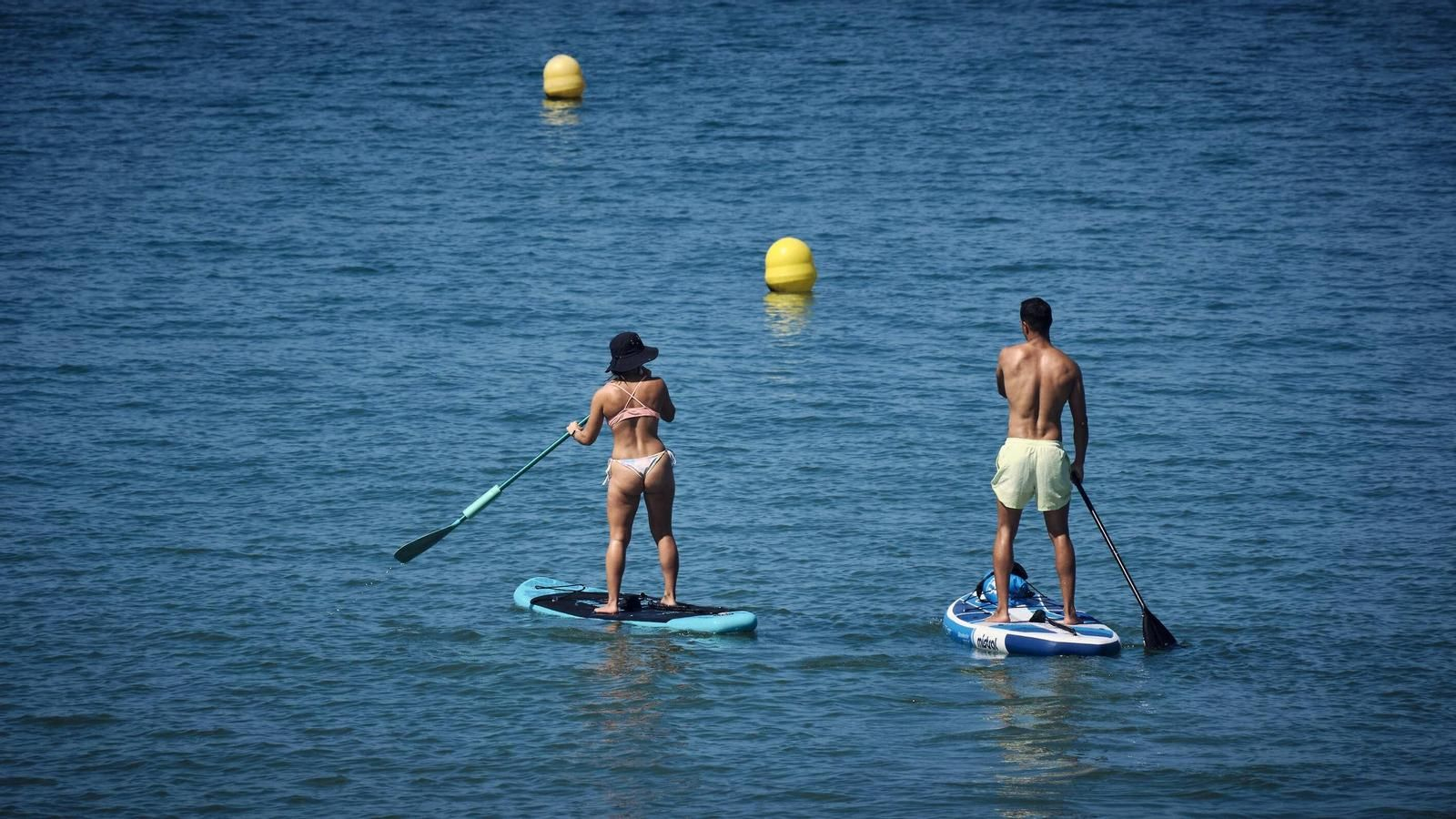 Dos personas practicando paddle surf en una playa de Cádiz.
