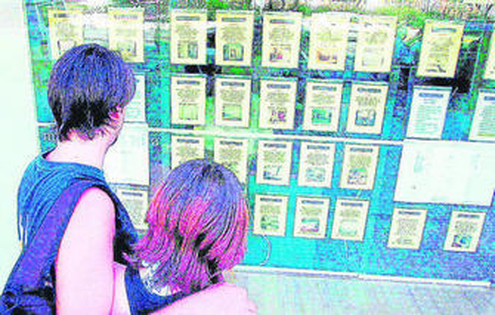 Una pareja de jóvenes, frente al escaparate de una inmobiliaria de la provincia de Cádiz.