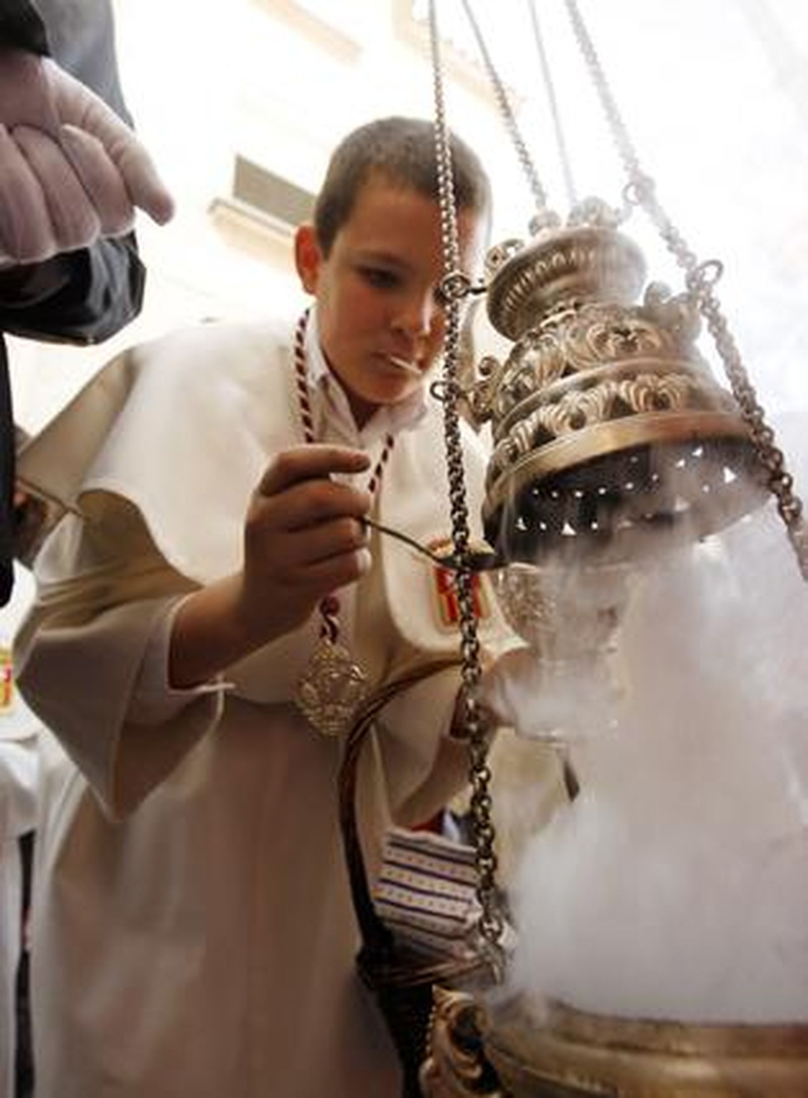 El monaguillo vierte con profusión incienso en el incensario.

Foto: Juan Carlos Toro