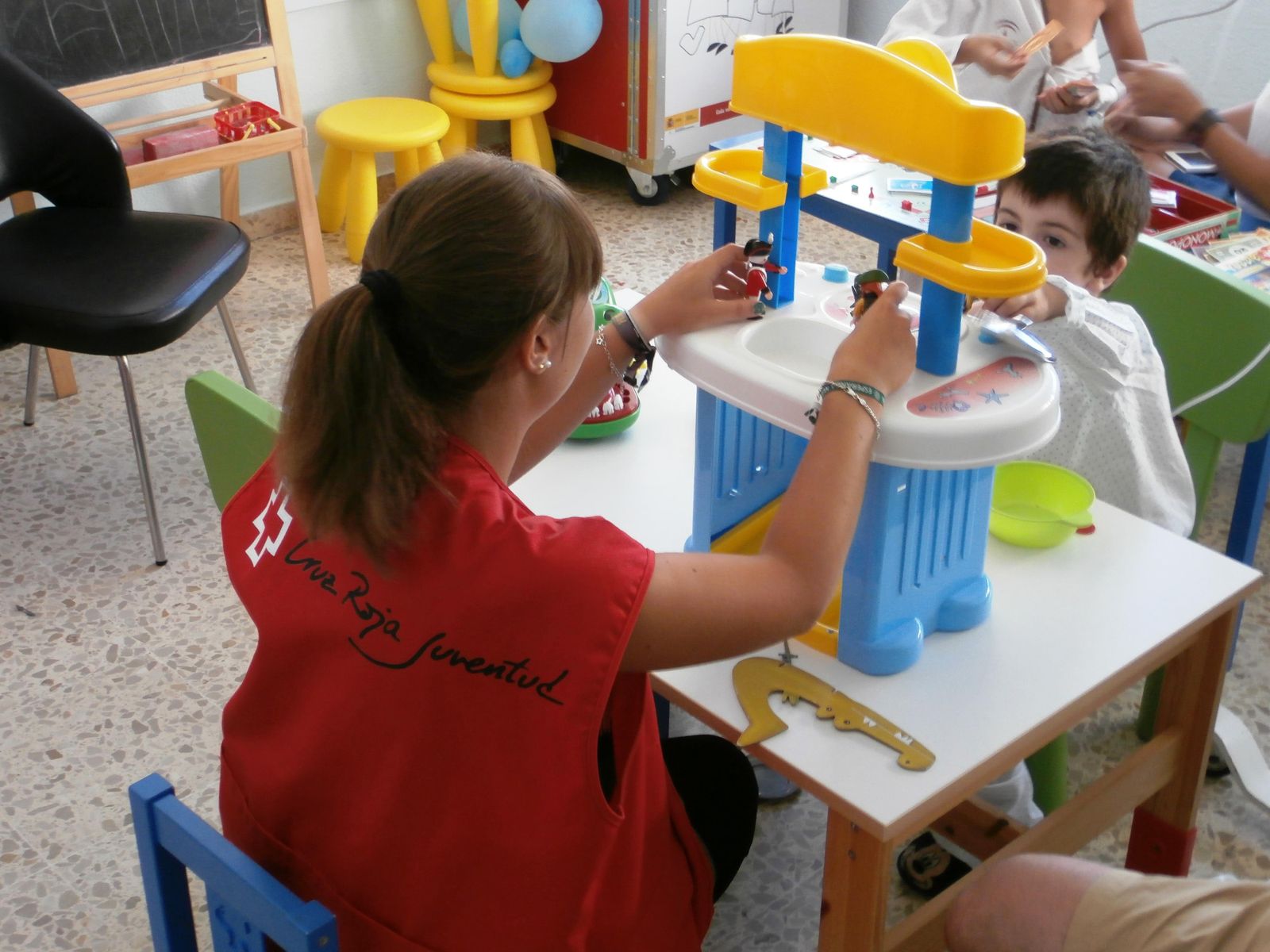 Una voluntaria de Cruz Roja acompaña a niños hospitalizados.