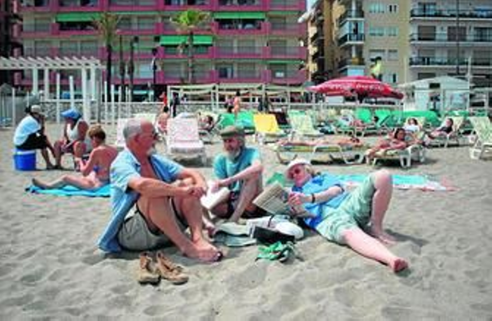Un grupo de extranjeros toman el sol en la playa.