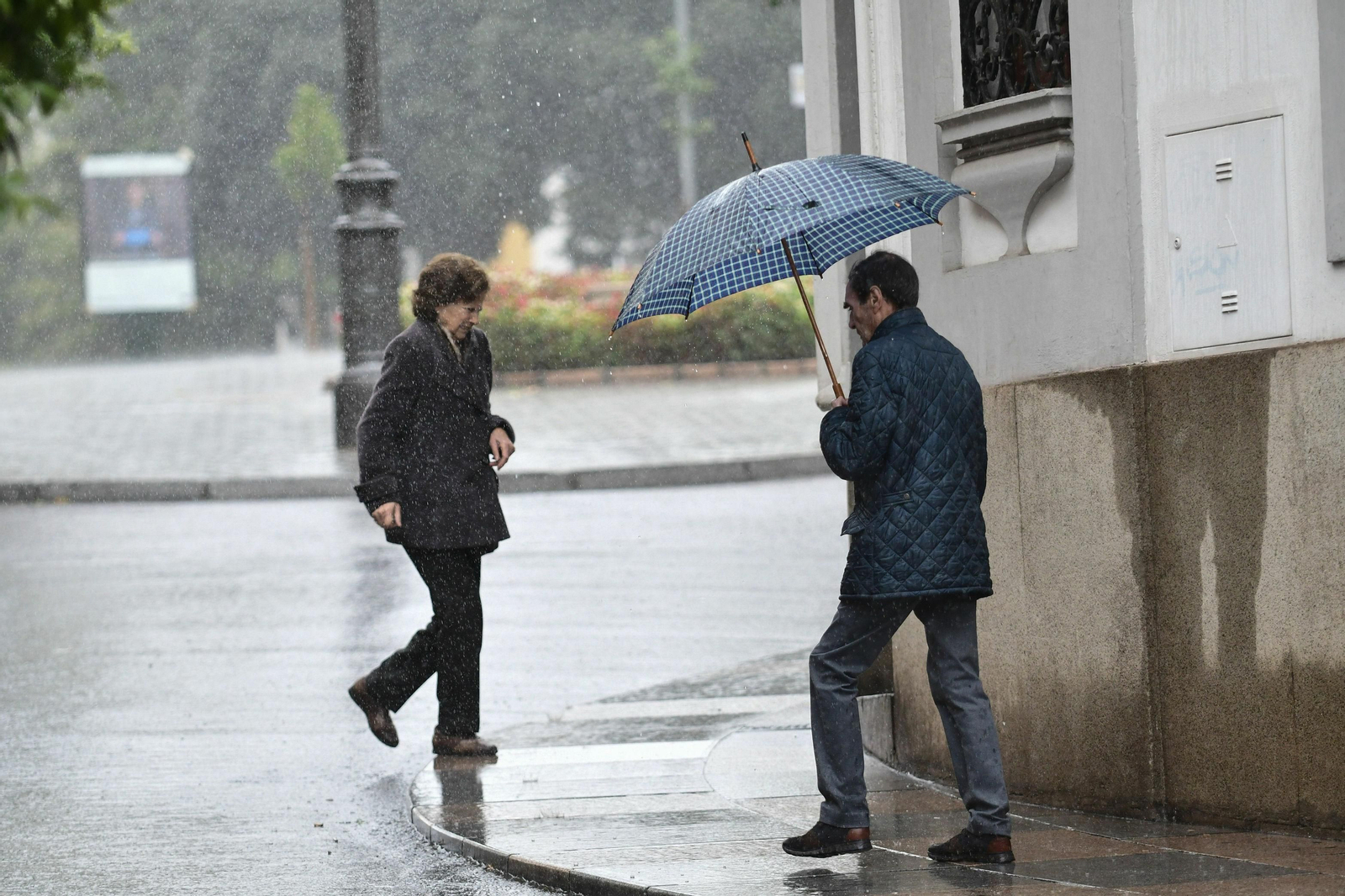 Dos personas caminan bajo la lluvia por el centro de la capital.