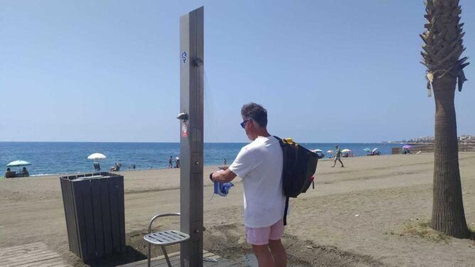 Un hombre enjuaga un bañador en una ducha.