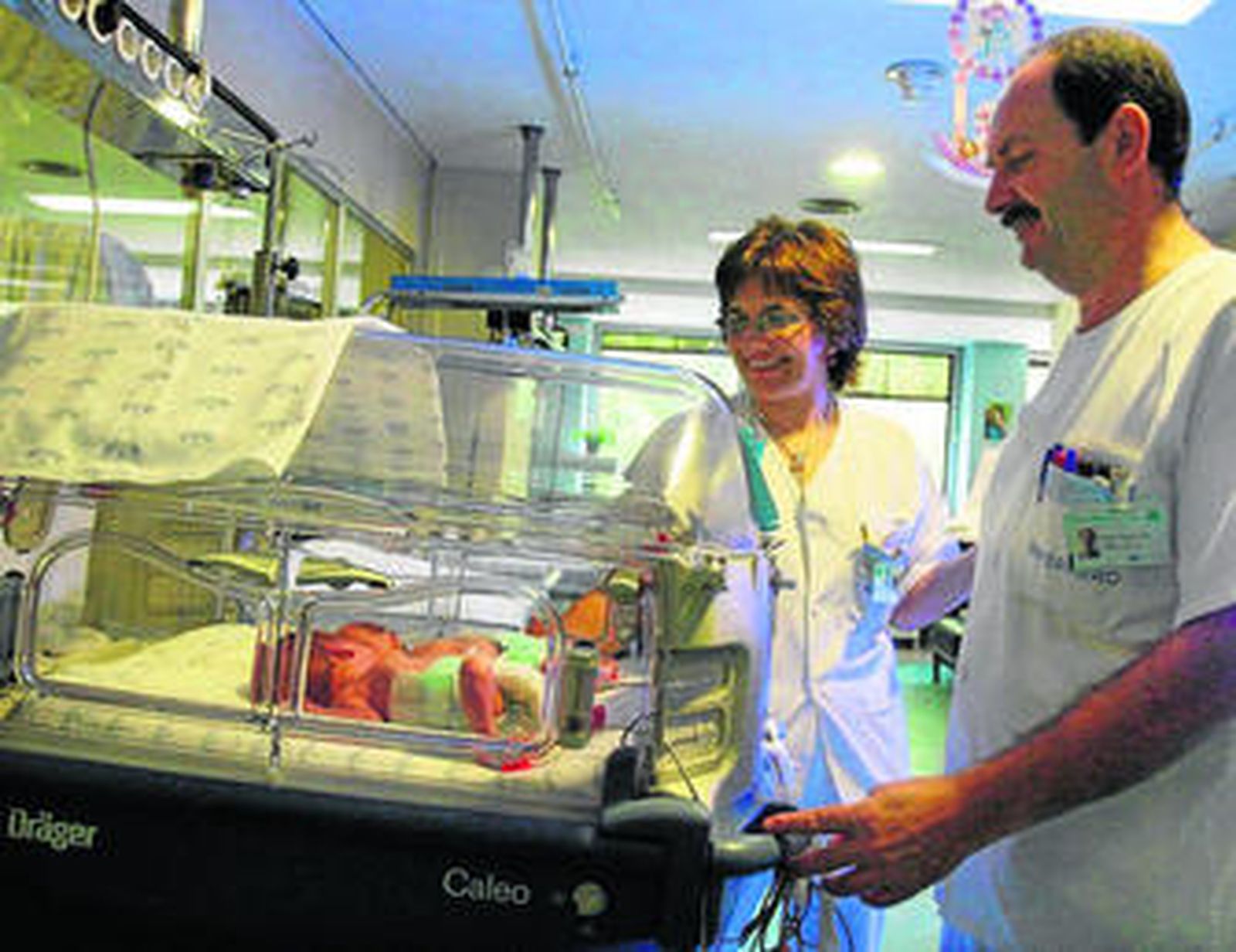 Dos enfermeros de Neonatología  supervisan a dos niños prematuros.