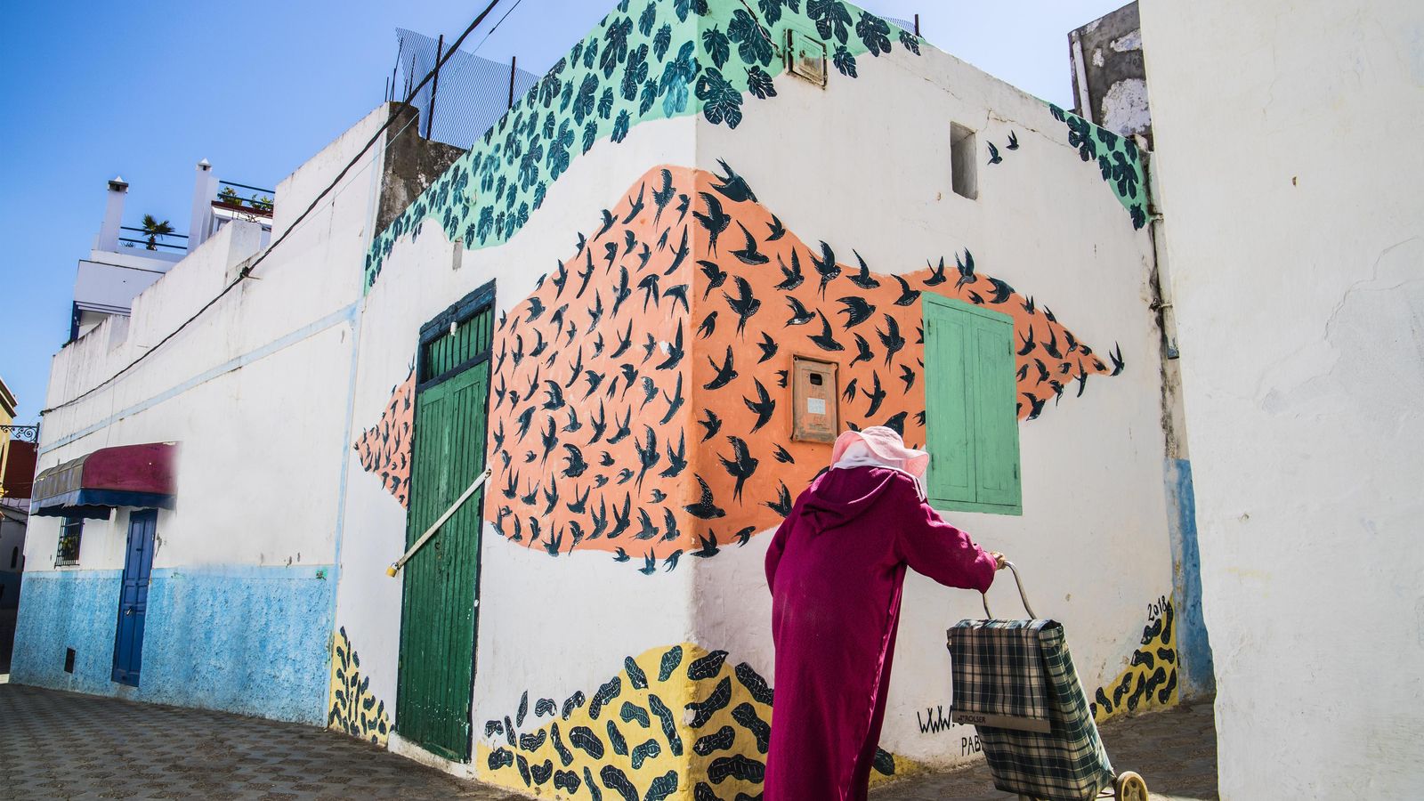 Una mujer con su carrito de la compra pasea por el centro de Asilah