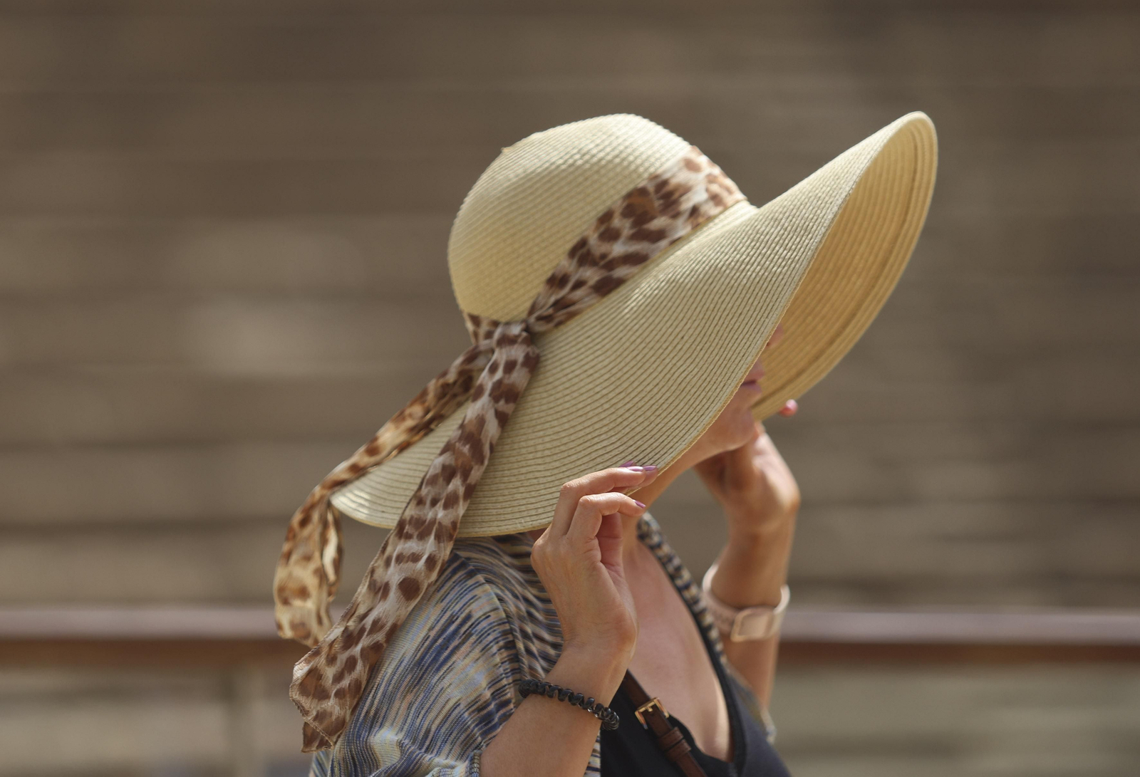 Una mujer se ajusta el sombrero para protegerse del sol en Málaga.