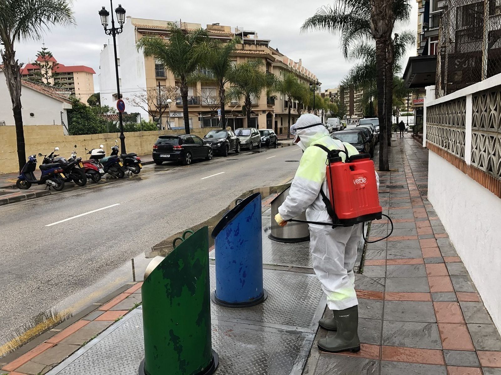 Un operario municipal limpia las islas ecológicas con una mochila de desinfección.
