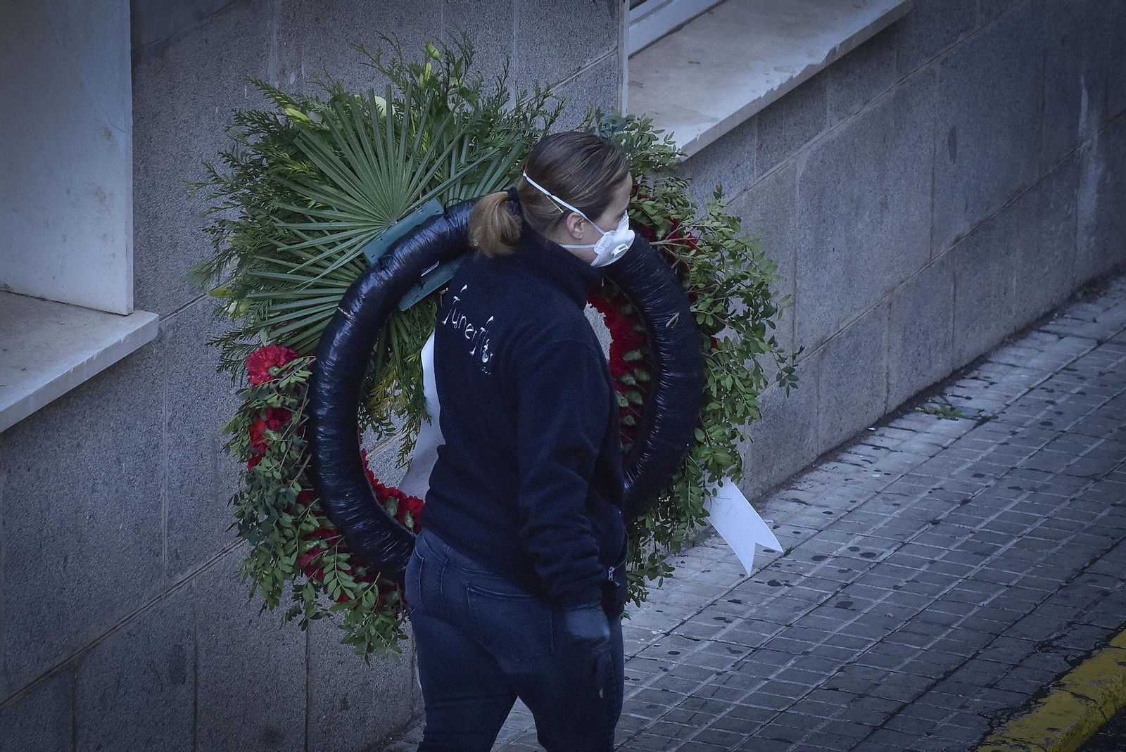 Una mujer transporta una corona de flores después de la muerte de una persona con Covid.