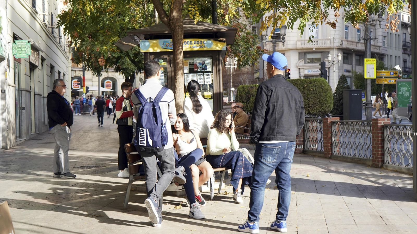 Varios jovenes descansan en los bancos de la Acera del Darro