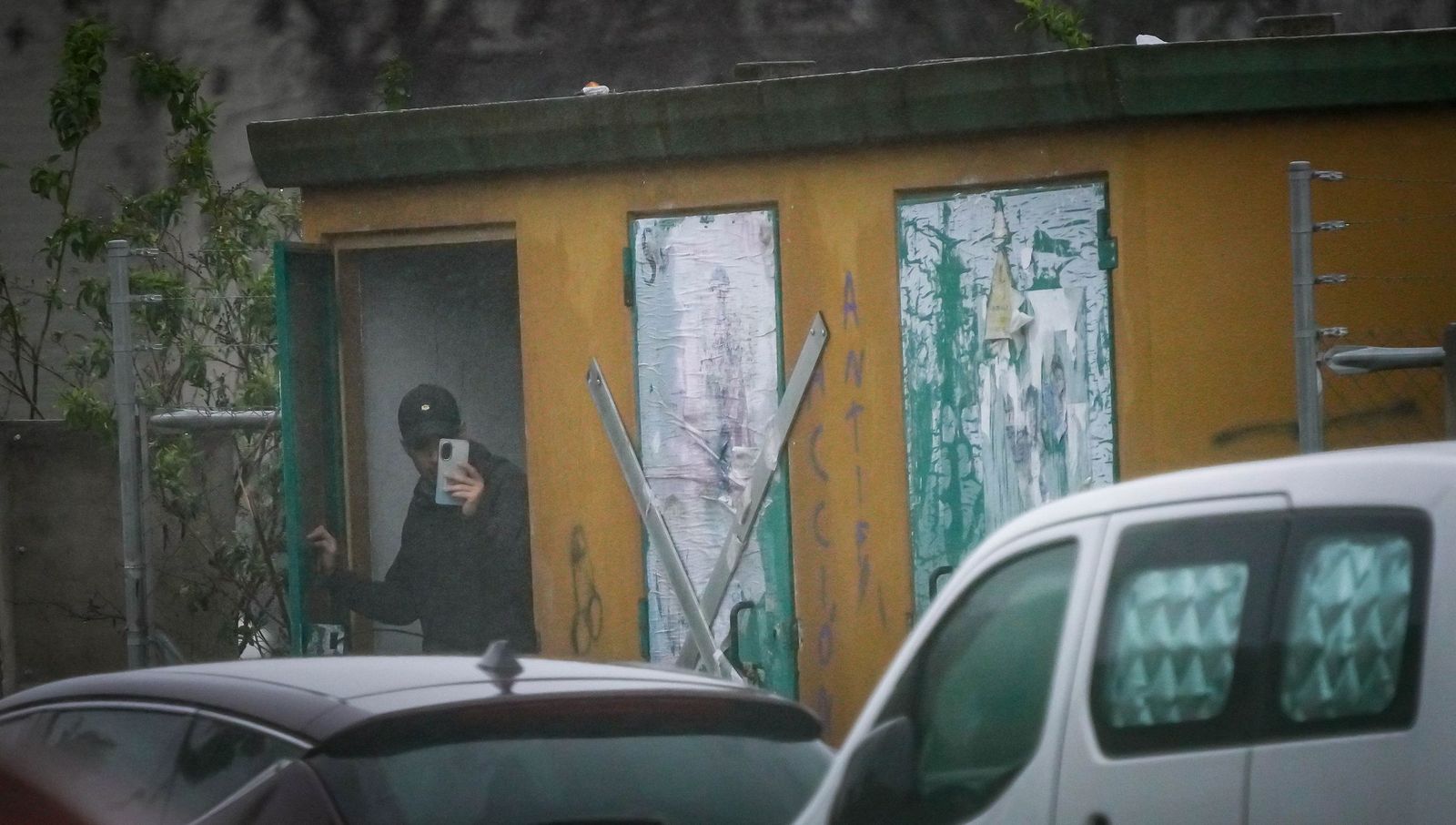 Uno de los jóvenes con su móvil, en el interior de una de las casetas de luz de Puertas del Sur.