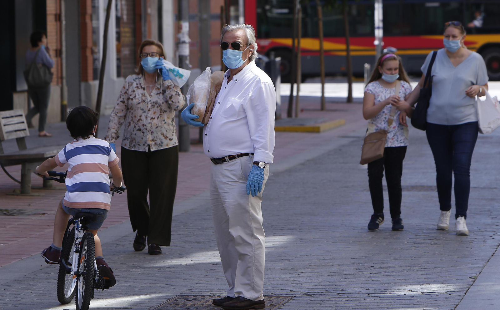 Varias personas con mascarilla de distintas edades coinciden en la calle.