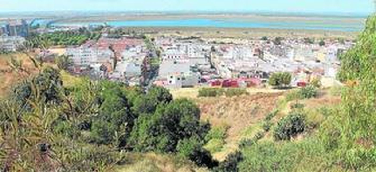 Las laderas se proyectan sobre la barriada de las Colonias, con el fondo de las Marismas del Odiel.