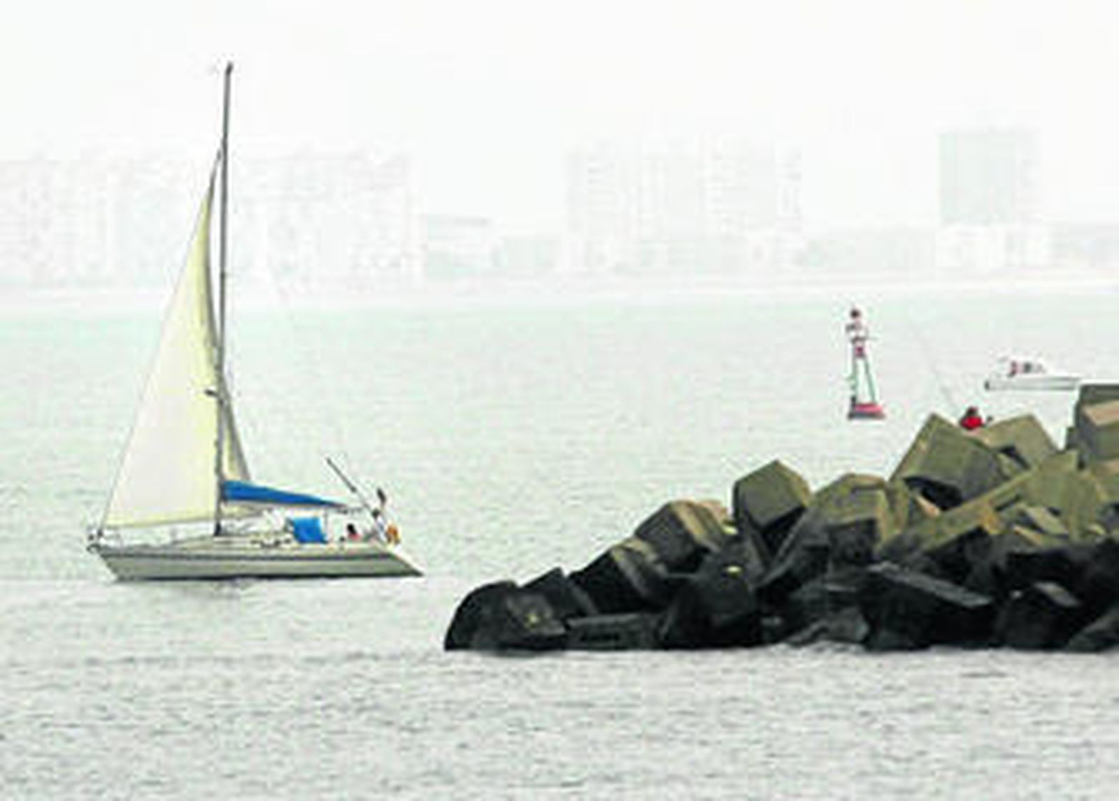 Uno de los barcos participantes deja atrás el espigón de la Punta de San Felipe, en Cádiz.