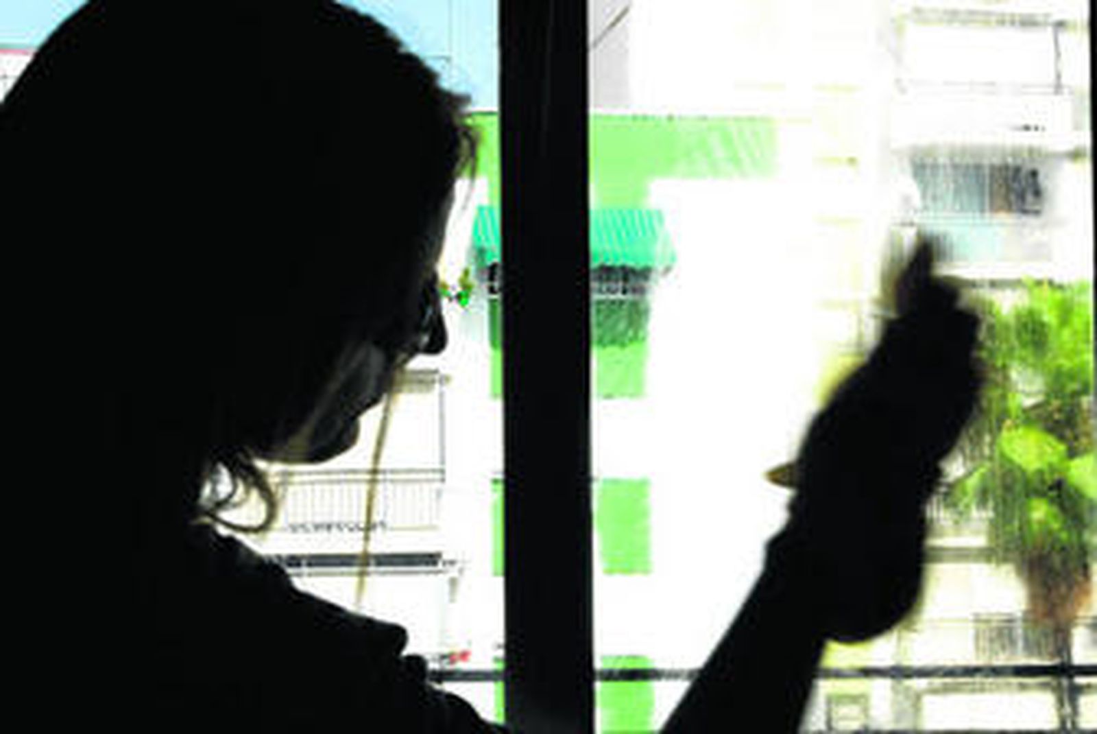 Una mujer limpia los cristales de su casa.