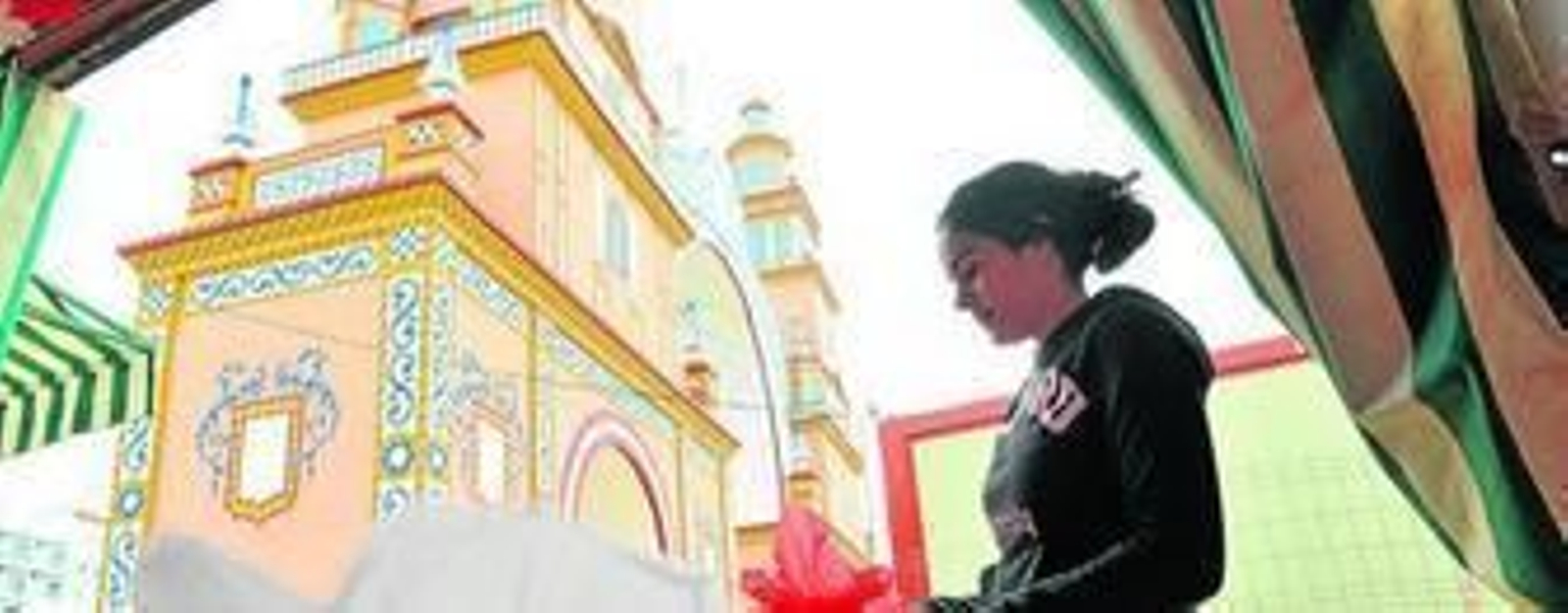 Una joven coloca adornos en una caseta próxima a la portada.