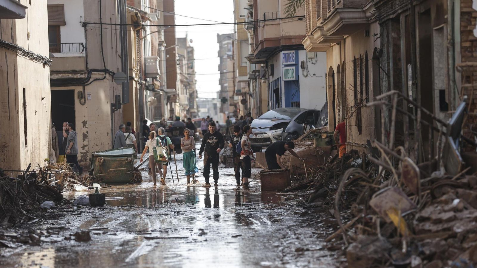 Varias personas caminan entre el lodo acumulado en las calles de Catarroja