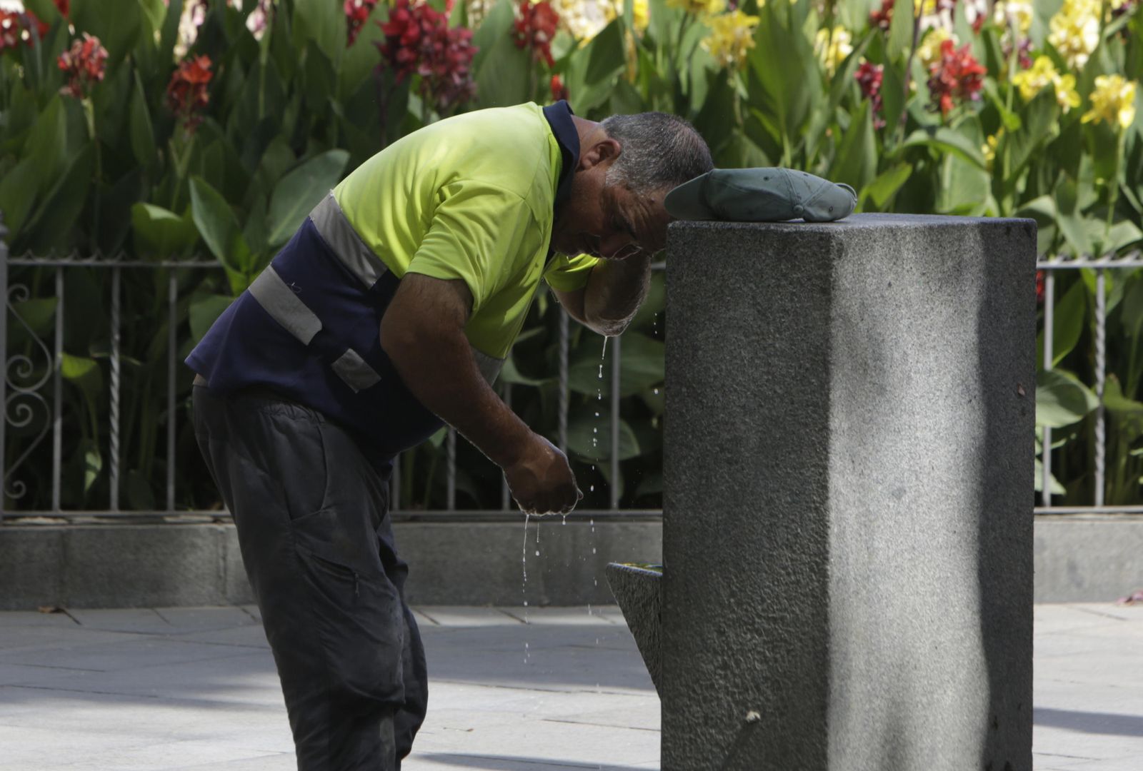 Un operario se refresca en una fuente