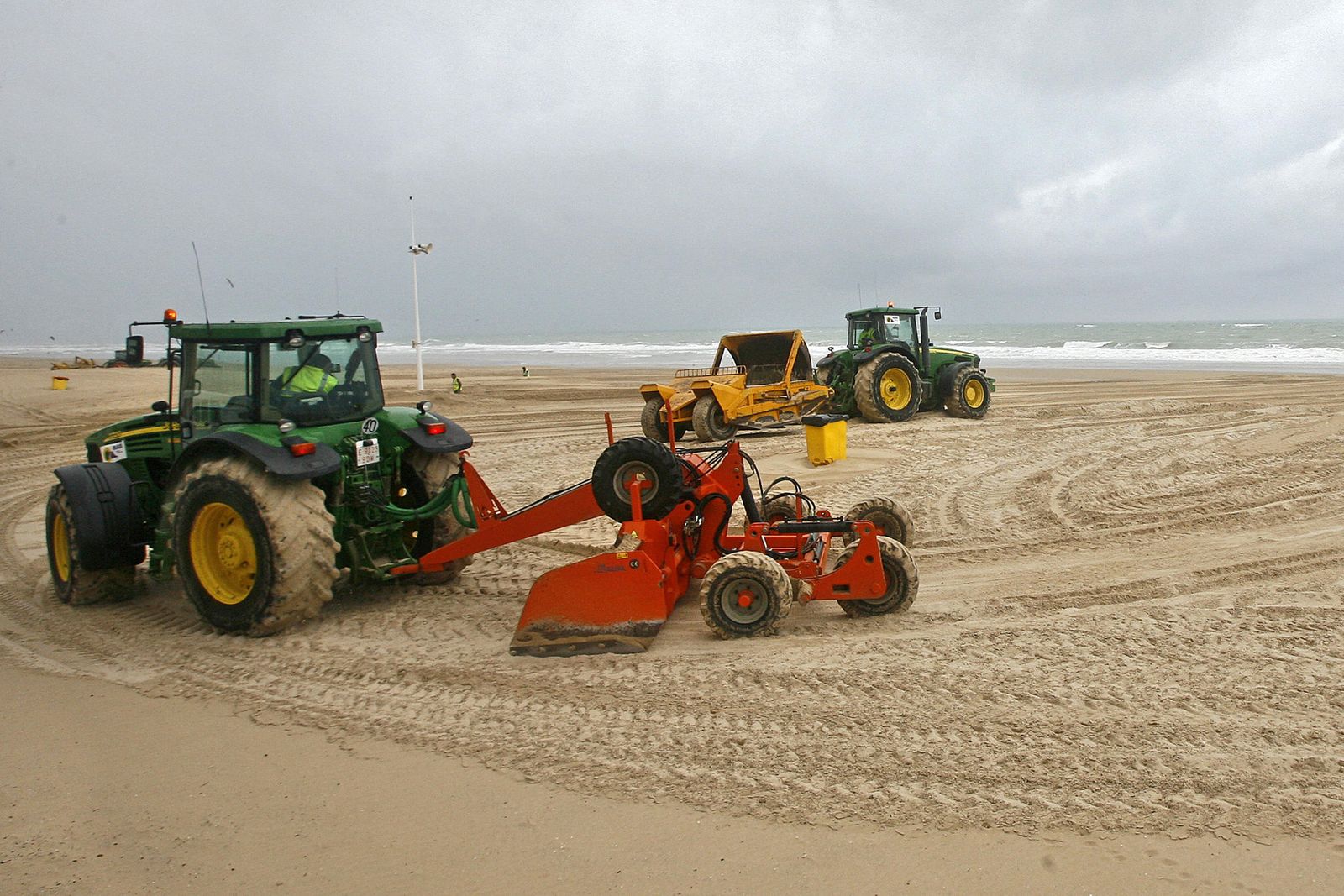 Dos tractores trabajan sobre la arena de la playa de la Victoria.