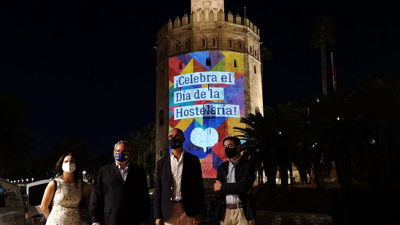 Las autoridades municipales y representantes de los hosteleros ante la Torre del Oro iluminada.