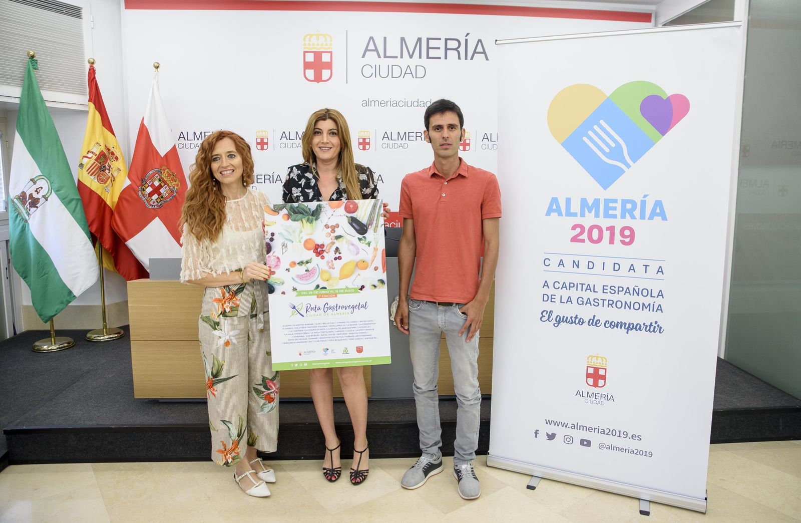 Yolanda Granados, Carolina Lafita y Cristian Rodríguez posan con el cartel del evento.
