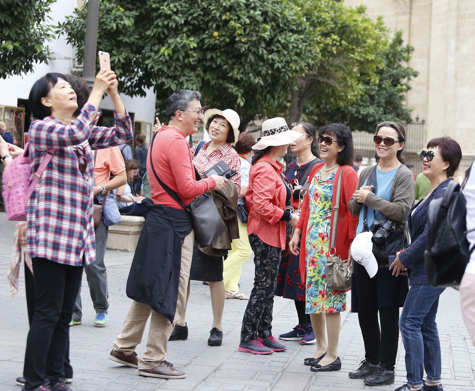 Un grupo de turistas asiáticos se fotografían junto a la Catedral de Sevilla.