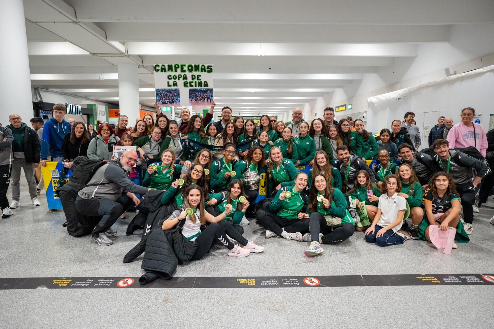 Las campeonas posan con los aficionados y niños de la cantera que acudieron a recibirlas al Aeropuerto de Sevilla.