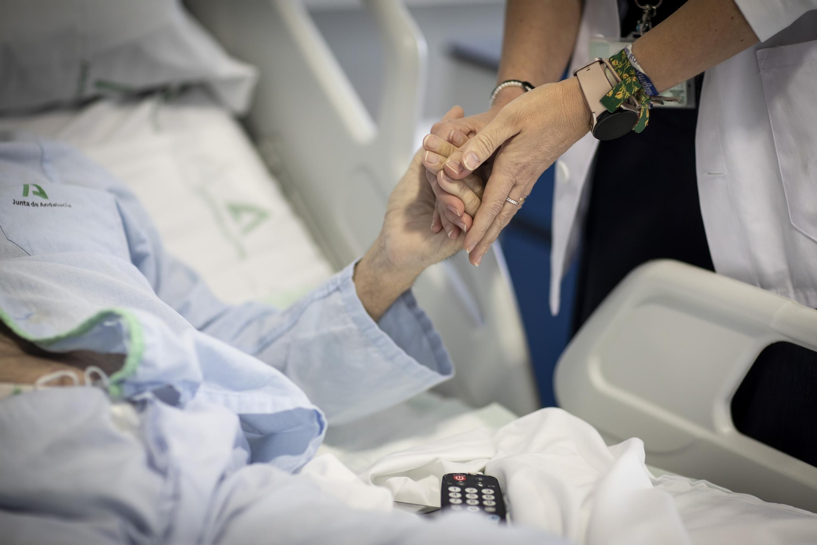 Alicia Bedmar sosteniendo la mano de su paciente, Antonio