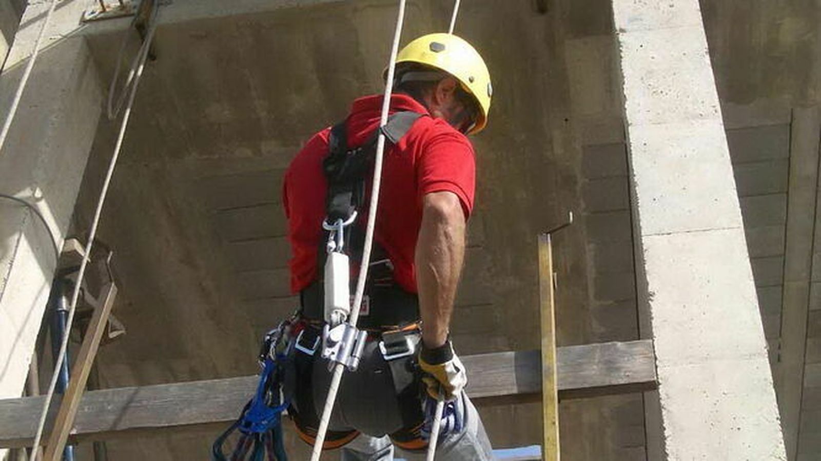 Un trabajador de una obra usando el arnés y sujeciones para prevenir riesgo de caídas