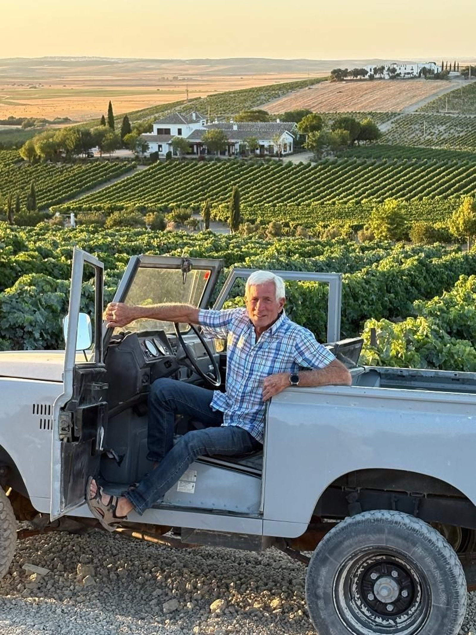 El propietario Noel Robyn.  delante de las viñas con la casa al fondo.