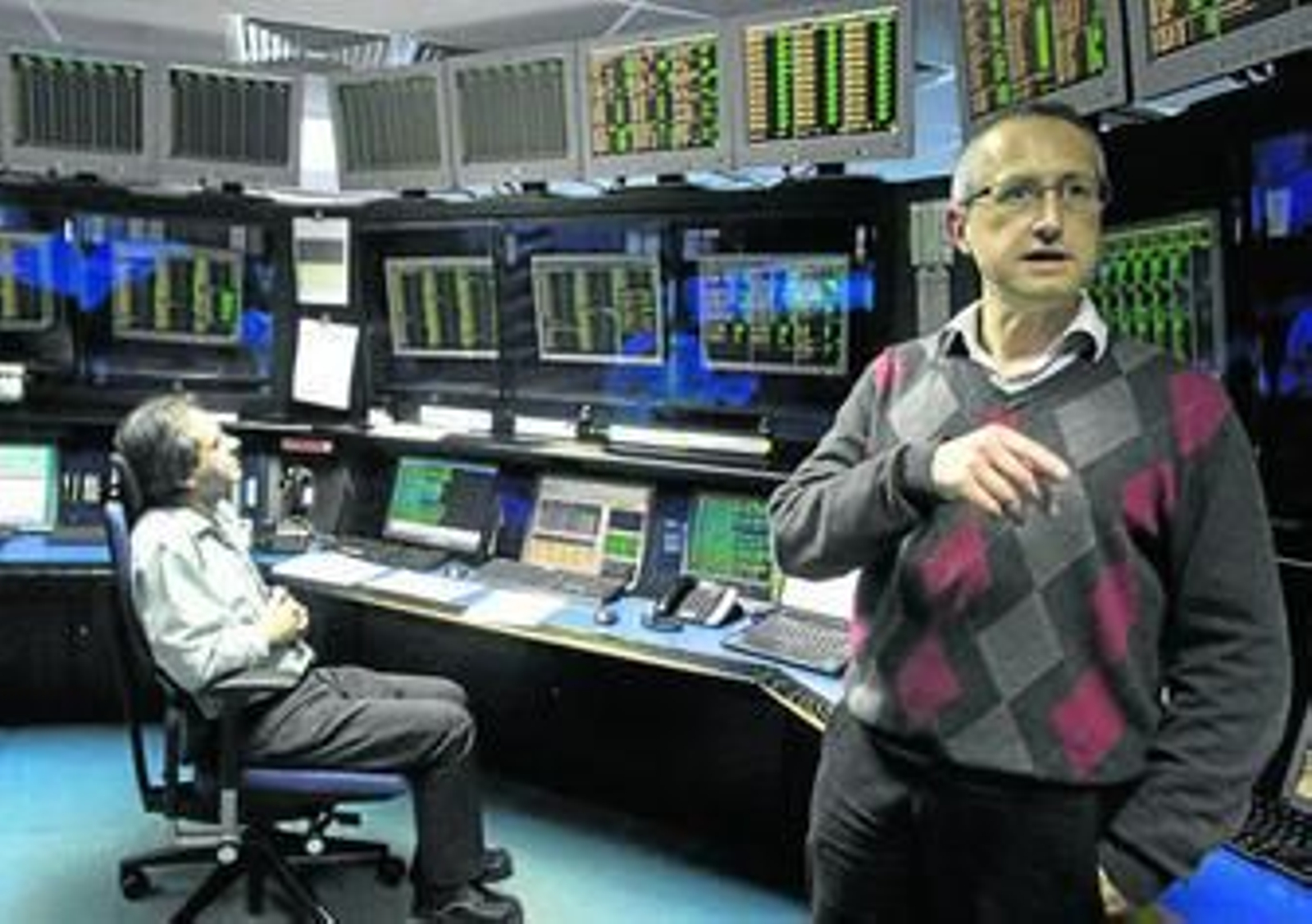 El director de la estación, Harry Pallas, explica el funcionamiento del centro mientras el controlador Ray Payas está atendiendo a las pantallas.