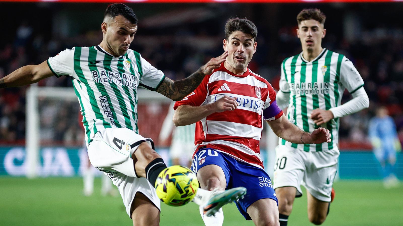 Álex Martín despeja el balón en pugna con Sergio Ruiz en un lance del Granada CF - Córdoba CF.