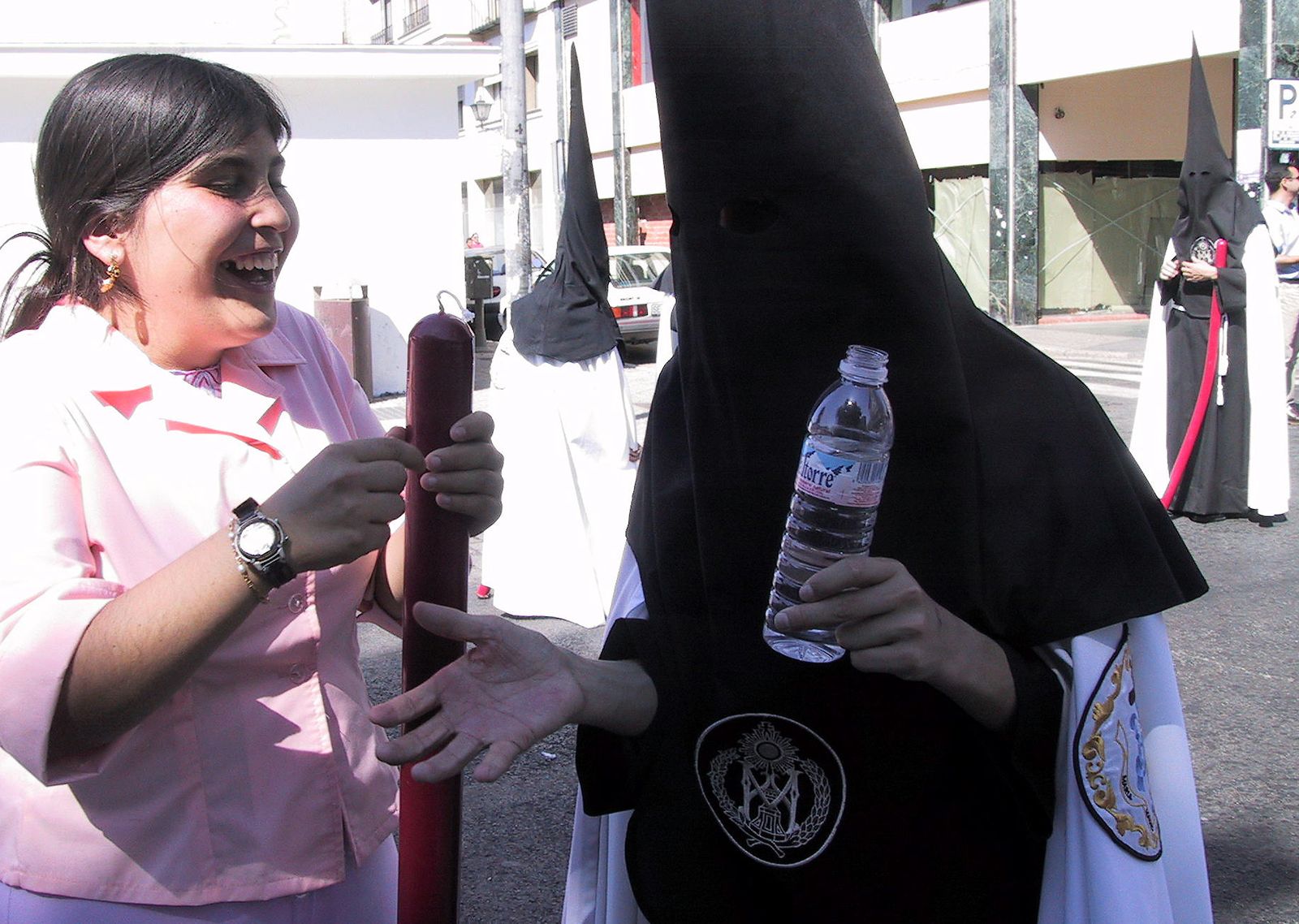 Un nazareno con una botella de agua  para combatir el calor.