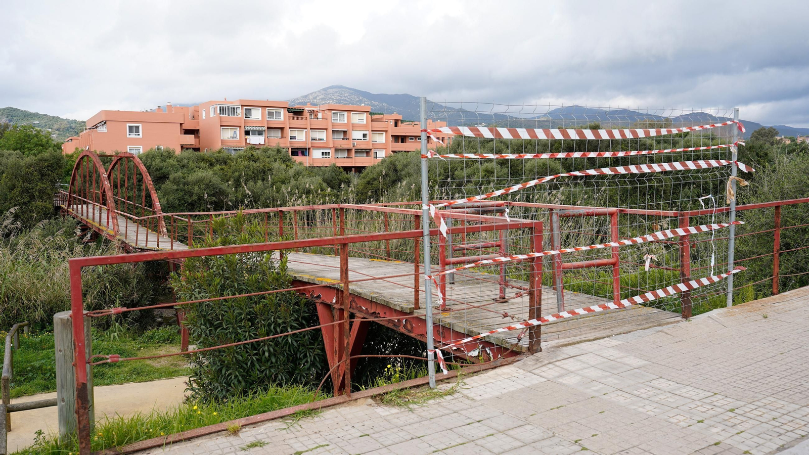 El puente sobre el río Pícaro cerrado y, de fondo, las viviendas de los camarotes de Getares.