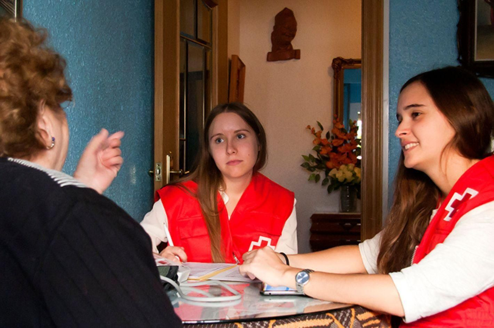 Voluntarias de Cruz Roja junto atienden a una persona mayor.