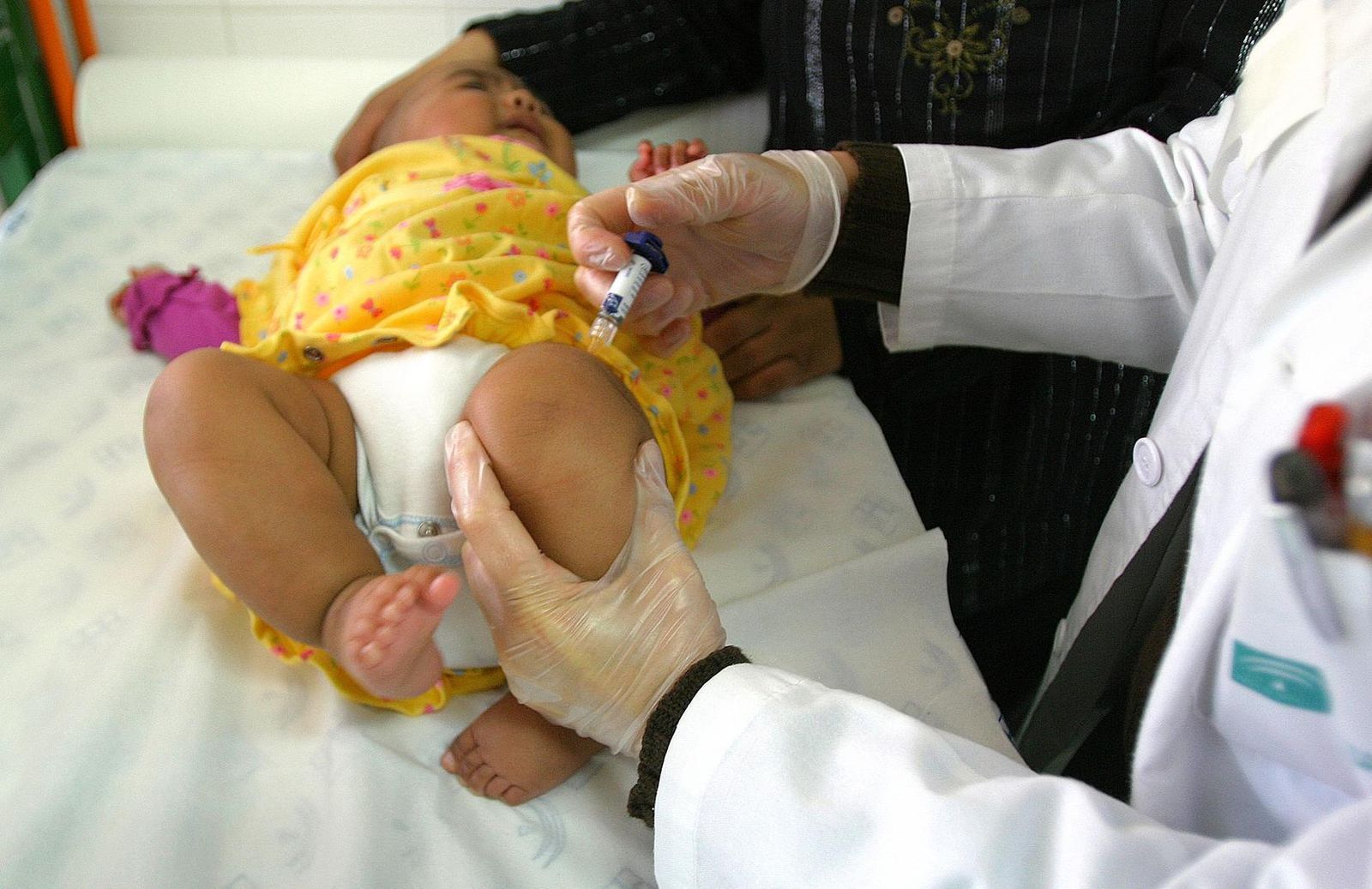 Un médico pone una vacuna a una niña.