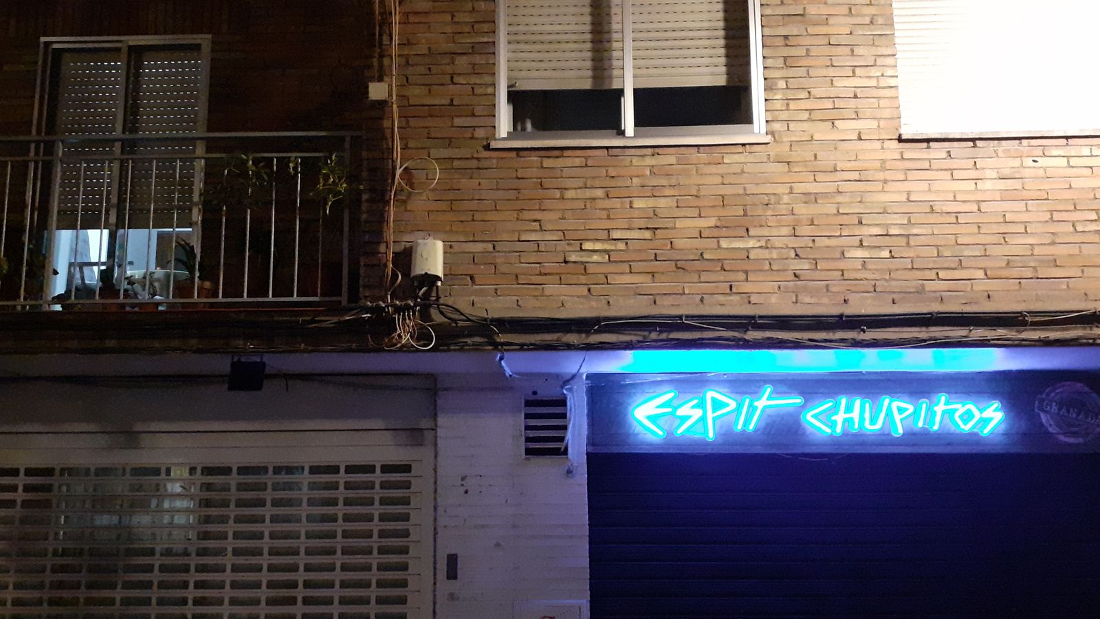 Una casa iluminada y el cartel de una chupitería de Pedro Antonio de Alarcón con la persiana bajada