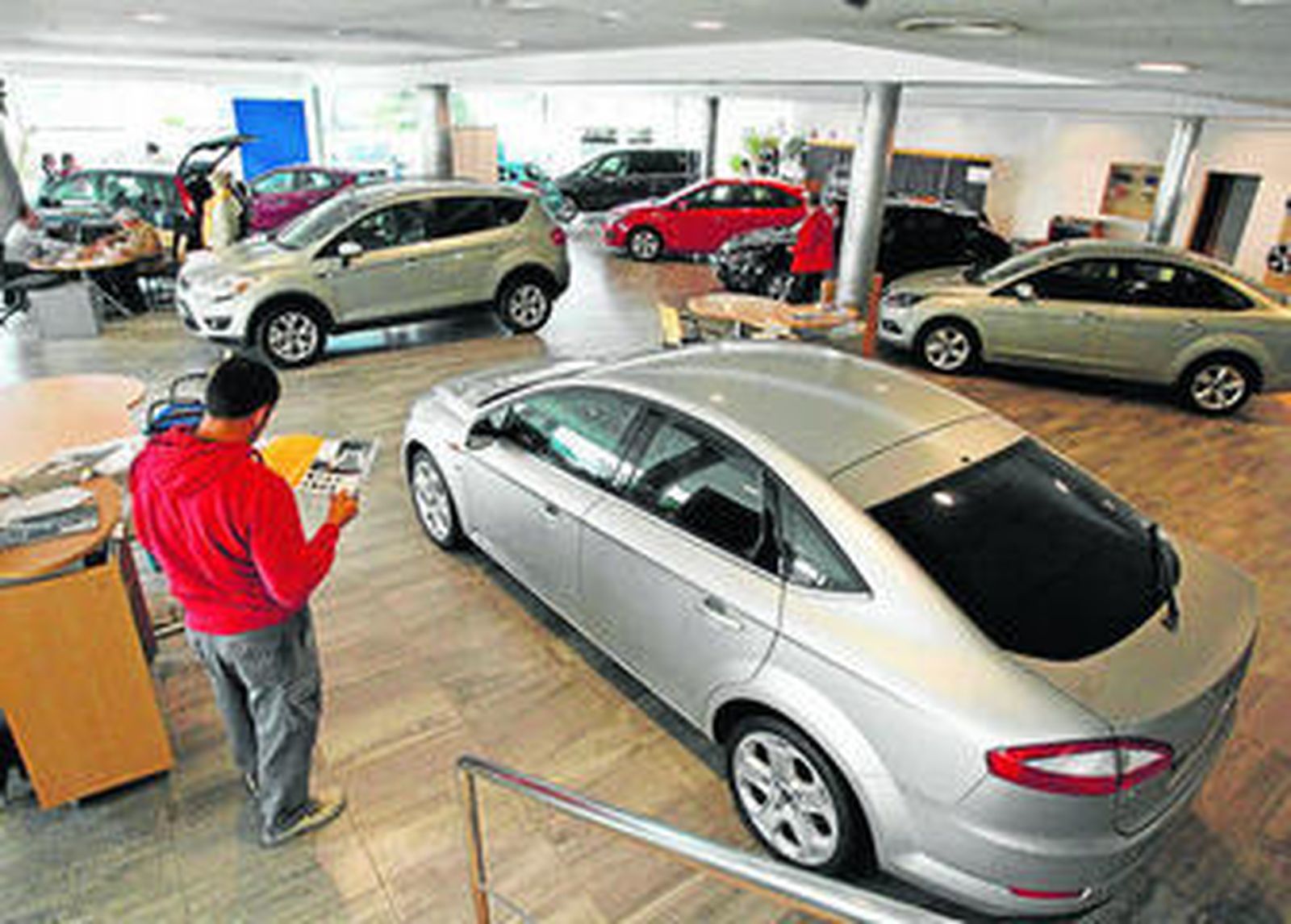 Varias personas en un concesionario de automóviles.