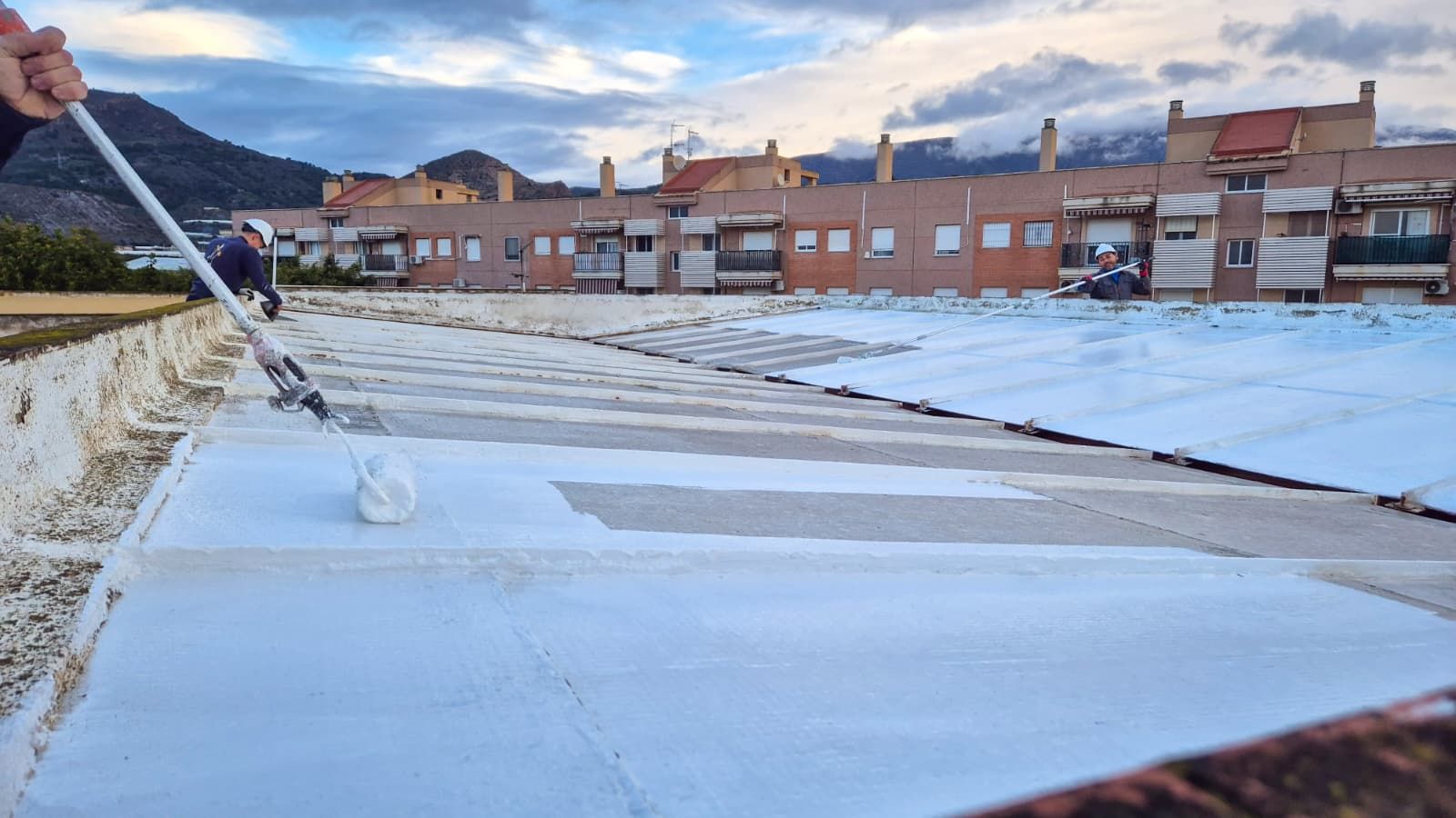 Varios trabajadores impermeabilizando el tejado del centro