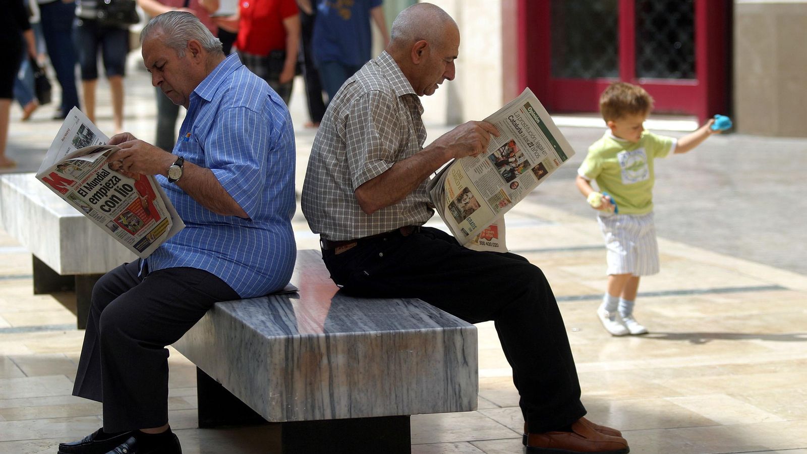Dos hombres leen el periódico en la calle. Dos hombres leen el periódico en la calle.