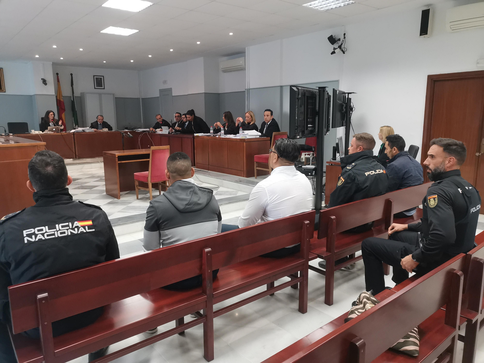 Los acusados, escoltados por policías, en el banquillo.