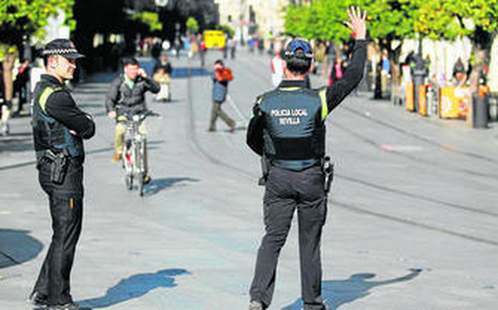 Dos policías locales paran a los ciclistas que circulan con auriculares en la Avenida de la Constitución.