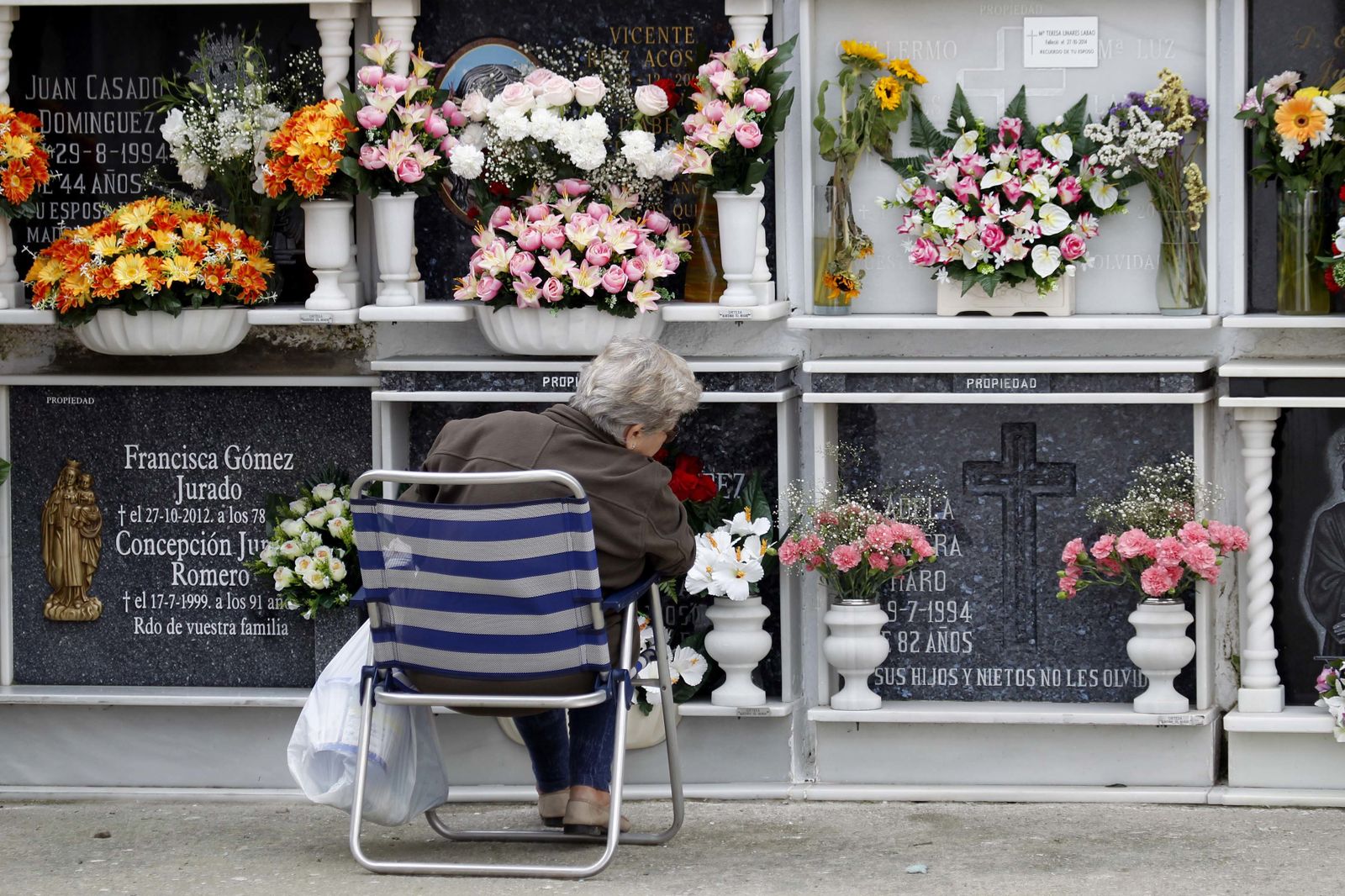 Una mujer, sentada frente a una lápida.