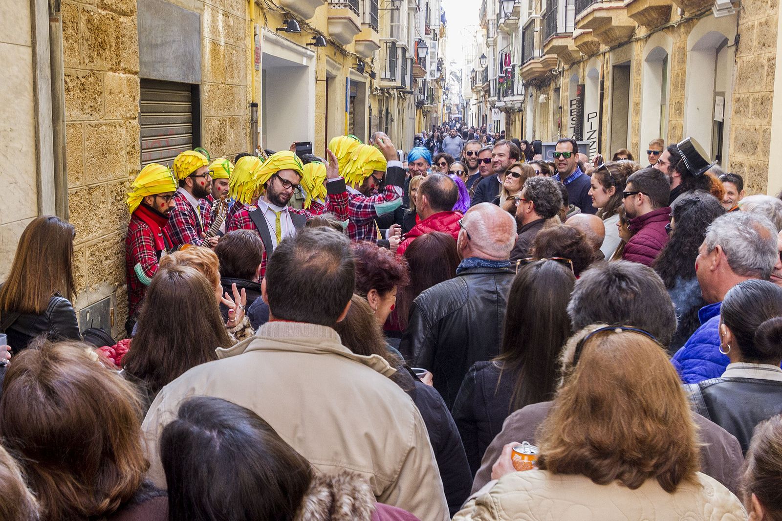 Una vía abarrotada de público mientras actúa una agrupación callejera.