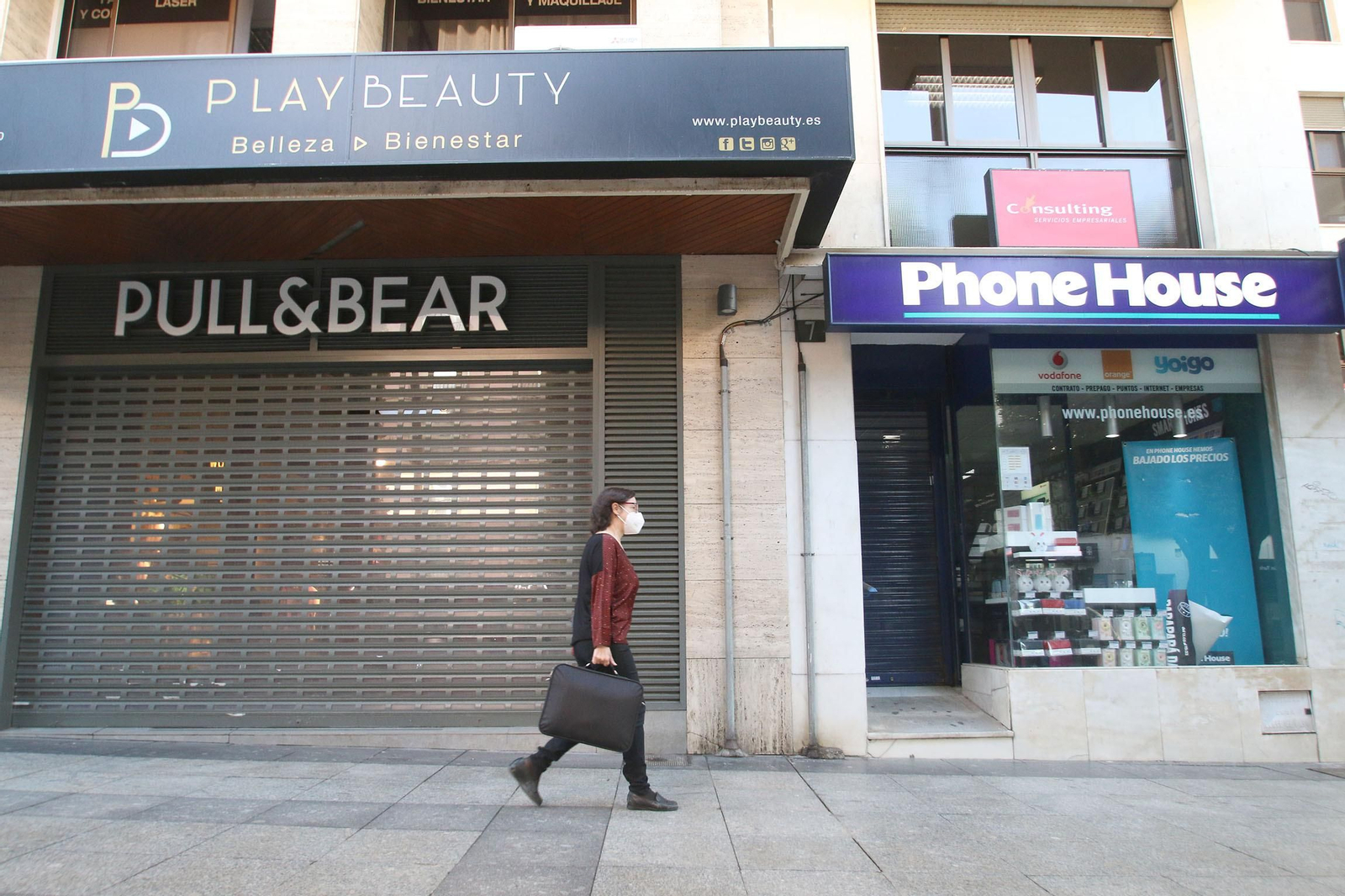 Una mujer pasa por un comercio cerrado en pleno confinamiento